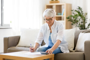 Woman sitting on sofa trying to figure out the Medicare part B penalty